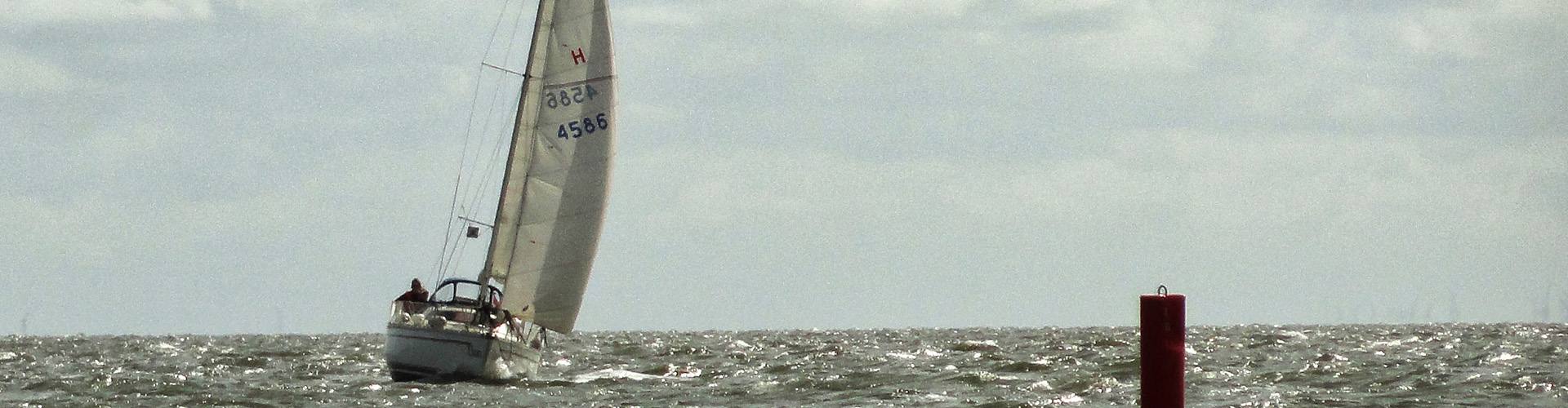 Twee opvarenden in de kuip van de Elan onder de rood-gele spinnaker, op zonnig water